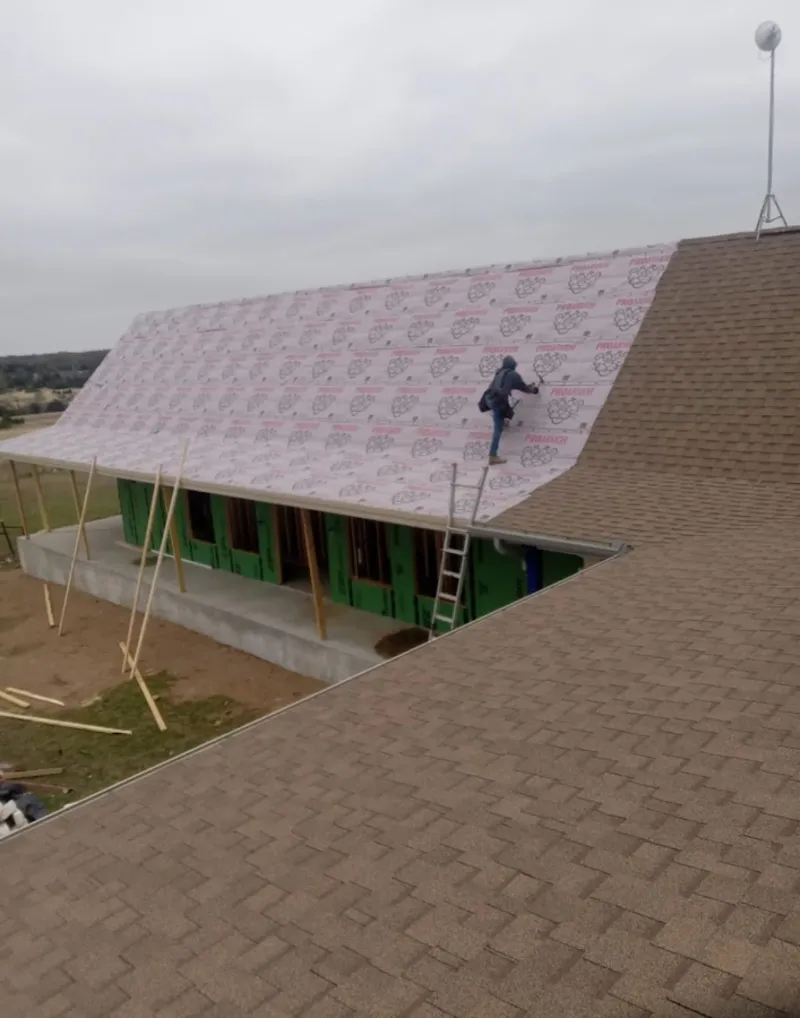 Worker preparing underlayment for a metal roof installation in Vinton